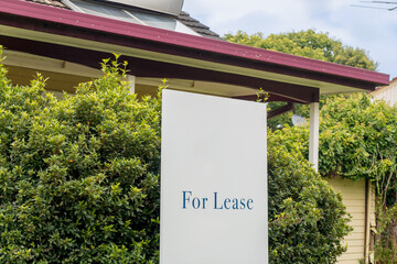 For lease sign on a white display outside of a house in Australia. Investment property real estate...