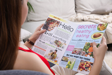 Young woman reading cooking magazine at home, closeup