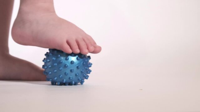 A child rolls an orthopedic ball with his foot. Foot exercise. 