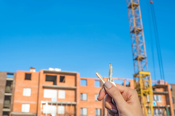 Construction of a new building or a new skyscraper.Construction site.Hands holding the keys to a new home.Mortgage for the construction of apartments.Buy real estate and property.Debt obligations