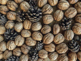 Autumn vibe background texture formed from walnuts and pine cones flat laid on table
