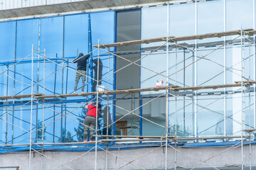 Fototapeta na wymiar Moscow, Russia,05,10,2021:Restoration, reconstruction and repair of the building. Construction workers are standing on scaffolding at the structure.Housing Restoration Construction Site