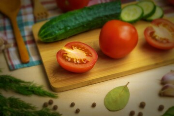 Fresh tomatoes, cucumbers, herbs and spices lie on a wooden table