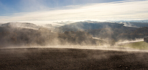 Brume fumante et nappe de nuage au lever du soleil en hiver dans les champs et les collines du Gers