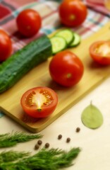 Juicy cream tomatoes and fresh green cucumber lie on a bamboo board