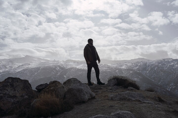 Fototapeta premium Silueta de hombre en una montaña mirando al horizonte mientras señala