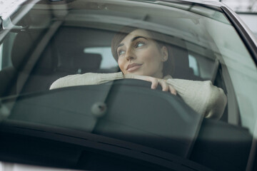 Woman sitting in car in a car showroom