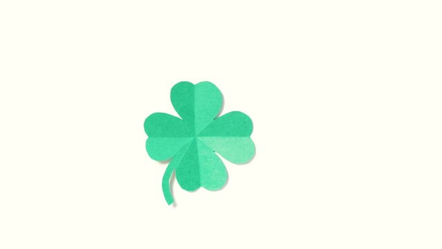 St. Patrick's Day. A leaf of clover cut out of paper is spinning on a white background. High quality 4k footage. vertical video