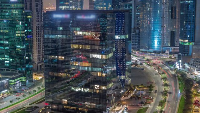 Business Bay Dubai skyscrapers with traffic on road intersection aerial night timelapse.