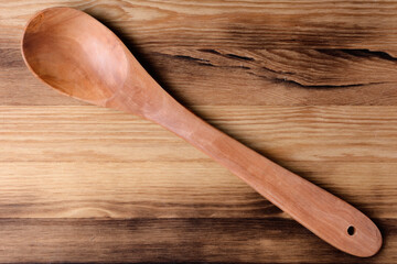 Wooden spoon with a long handle on an old wooden surface