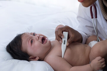 Sad crying caucasian baby girl visiting pediatrician doctor, African pediatrician checks the...
