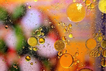 Öltropfen in Wasser auf einem bunten Untergrund.