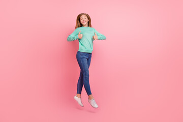 Fototapeta na wymiar Photo of sweet cute school girl dressed teal pullover jumping high thumbs up isolated pink color background