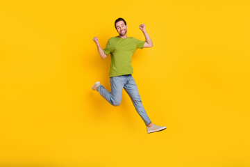 Full body photo of young man jump up rejoice victory fists hands goal awesome isolated over yellow color background