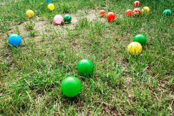 Many multi-colored plastic balls on green grass