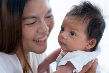 Asian mother holds a newborn baby in her arm, mom is smiling happily with her child, newborn 2 month year old  baby and mom concept, selective focus