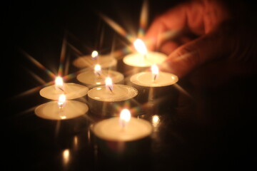 Man's hand lighting several candles on a wooden table