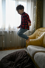 little boy at home having fun and jumping on the couch