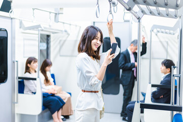 電車でスマホを使う若い女性