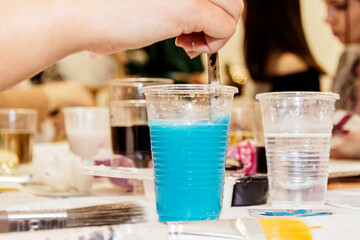 Blue watercolor paint in a plastic cup on the table