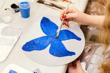 Girl painting a blue butterfly with watercolors closeup