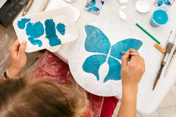 Girl painting a blue butterfly with watercolors