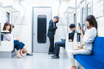 電車でスマホを使う若い女性