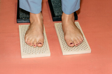 Woman's feet on a path made of Sadhu boards on a red background