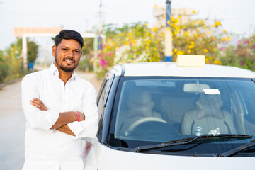 Happy confident cab driver with crossed arms standing next to car by looking at camera - concept of self-employed, positive emotion and profesional occupation.