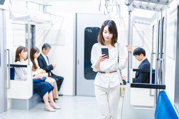 Fototapeta premium 電車でスマホを使う若い女性
