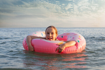 Summer vacation. Lovely girl with pink inflatable ring in blue water