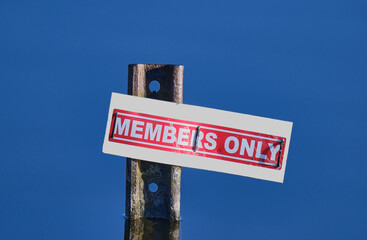 Members only sign on metal post in lake