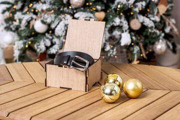 Black genuine leather belt in a box on a wooden table