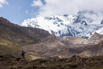 Tourist photographer against the backdrop of the snow-capped Himalayan mountains in the Manaslu region.
