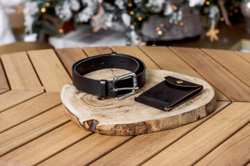 Black belt and wallet made of genuine leather on a wooden table