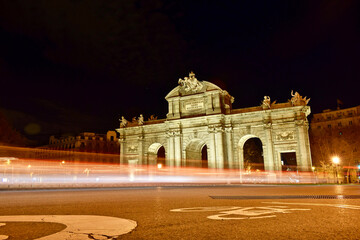 Puerta de Alcala at night and full moon. Light trail effect of vehicles passing through the Puerta de Alcala at night with full moon. Upward plane, the object is oriented to the left.