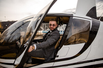 Rich man in a suit sitting in the cockpit of a personal helicopter