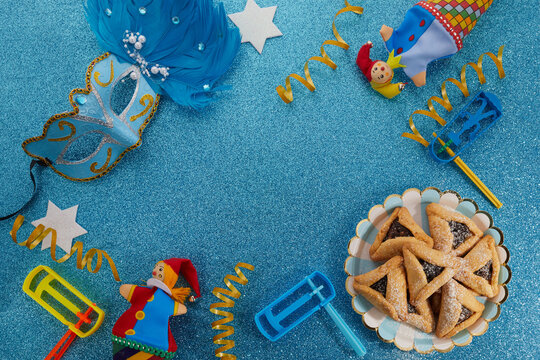 Jewish holiday Purim background with hamantaschen or hamans ears cookies, carnival mask and noisemaker
