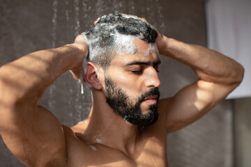 Handsome condifent young Arabic male model enjoying taking hot shower
