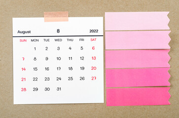 August 2022 calendar with blank adhesive note paper on brown background.