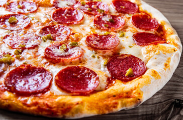 Hot Pepperoni Pizza with Mozzarella cheese, salami, Tomato sauce, pepper, Spices. Italian pizza on wooden background