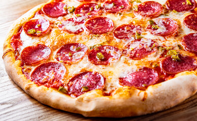 Hot Pepperoni Pizza with Mozzarella cheese, salami, Tomato sauce, pepper, Spices. Italian pizza on wooden background