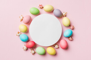 round frame multicolored Easter eggs with white blank paper on a brown background, close-up, space for text, blank for design, selective focus, tinted image