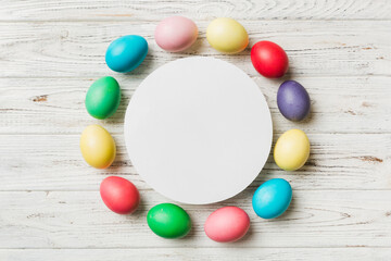 round frame multicolored Easter eggs with white blank paper on a brown background, close-up, space for text, blank for design, selective focus, tinted image