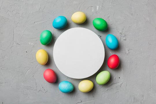 round frame multicolored Easter eggs with white blank paper on a brown background, close-up, space for text, blank for design, selective focus, tinted image