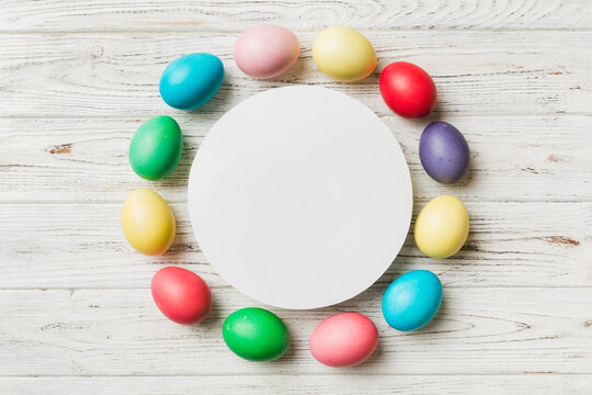 round frame multicolored Easter eggs with white blank paper on a brown background, close-up, space for text, blank for design, selective focus, tinted image