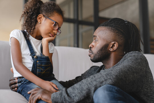 Loving african-american father dad listening to daughter`s problems with attention, supporting and calming her at home. Solving family problems. Fatherhood.