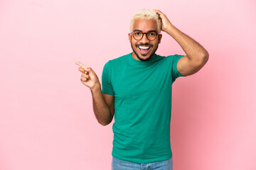 Young Colombian handsome man isolated on pink background surprised and pointing finger to the side