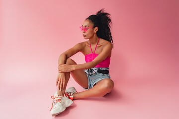 attractive black african american woman in stylish outfit on pink background