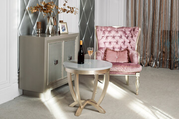 Luxury Interior. Luxurious pink velvet armchair, antique carved furniture, classic interior. Served wine in stylish restaurant waiting for a guest.